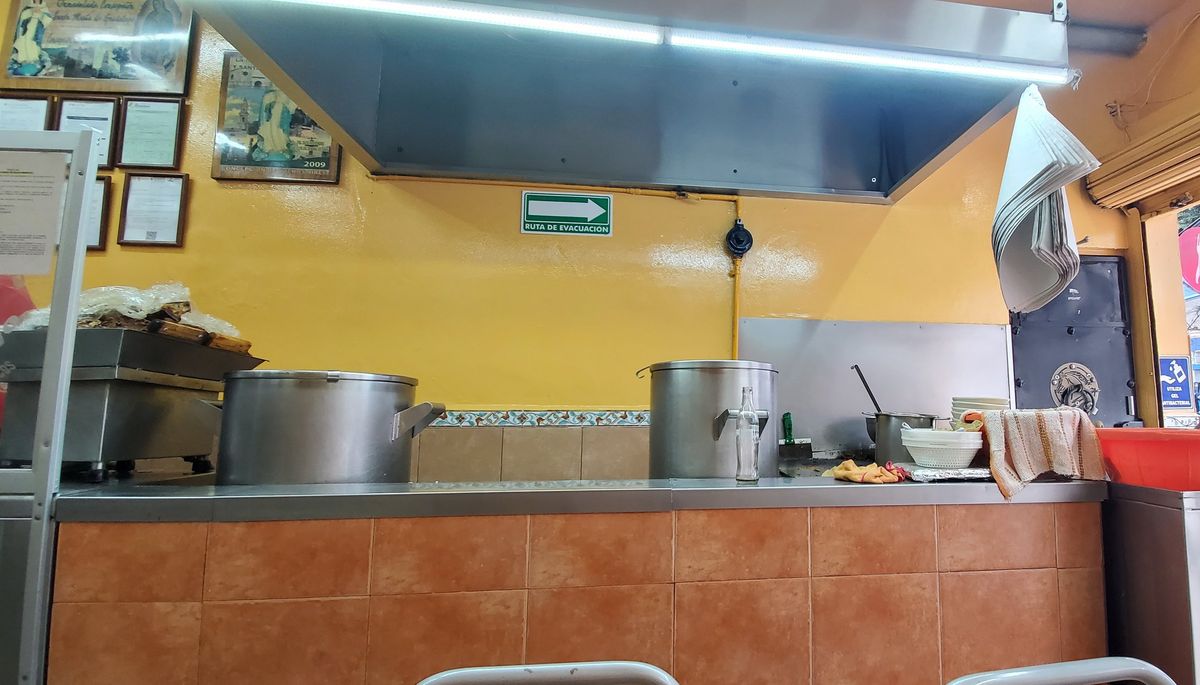 Cocina con ollas de acero, campana y barra revestida de azulejo